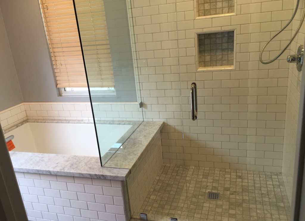 shower remodeling adds white subway tile to wall to match tile around soaking tub surround so both match