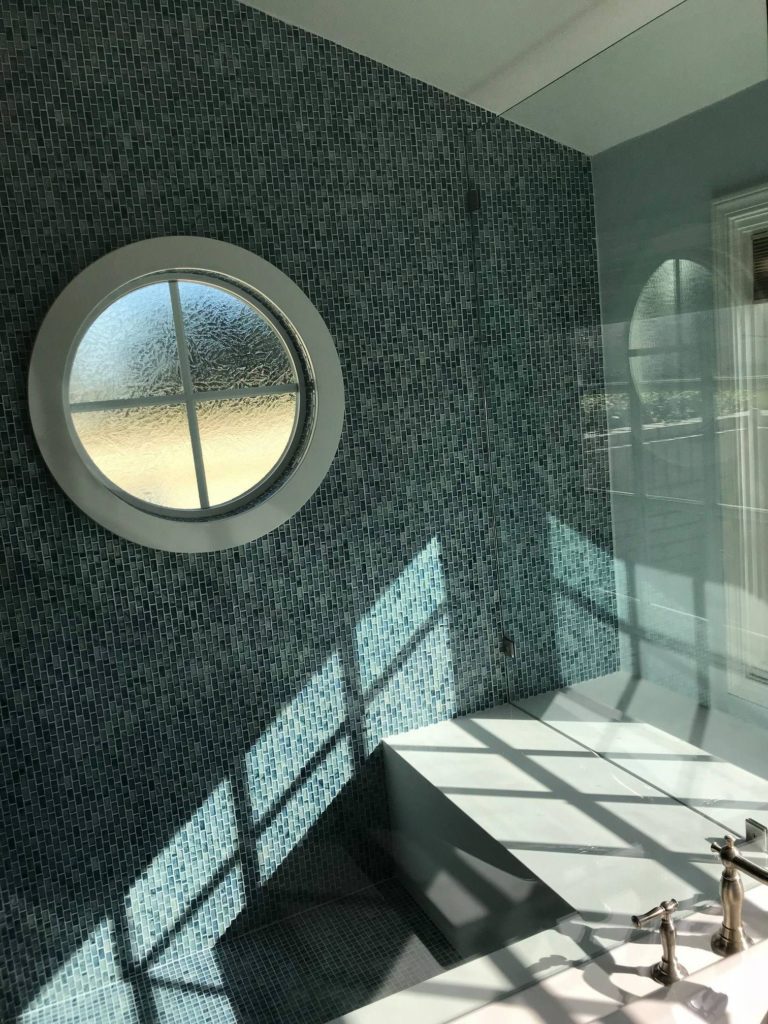 interior remodeling after of bathroom with blue tile and nautical inspired porthole window