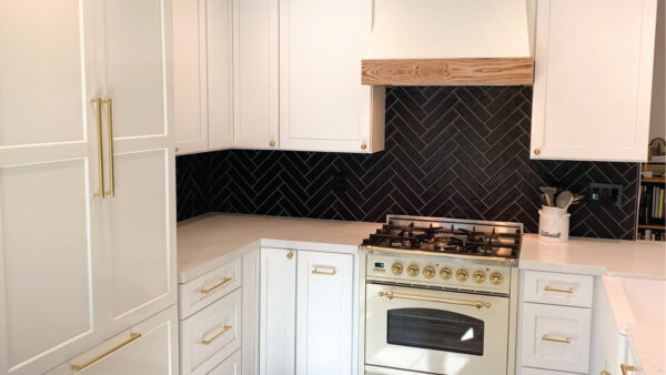 Farmhouse inspired kitchen with black herringbone backsplash and white cabinetry