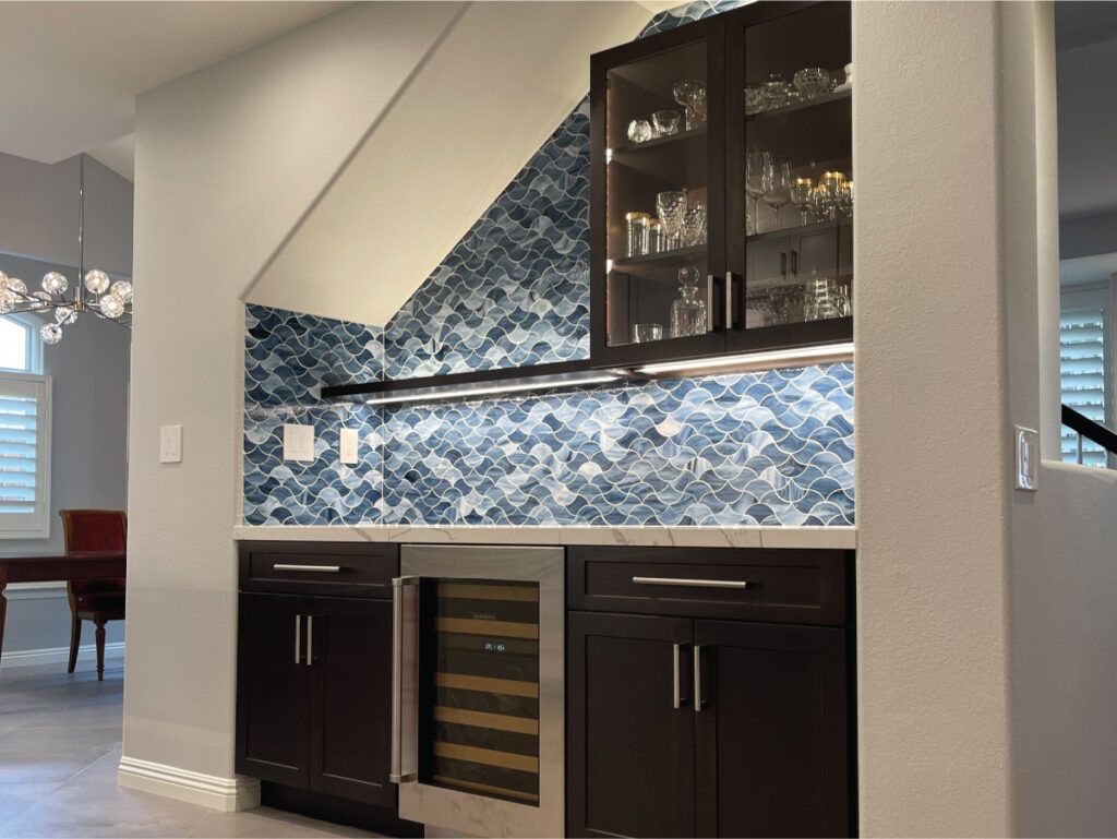 Home bar with custom blue glass backsplash in wave pattern and dark wood custom cabinets