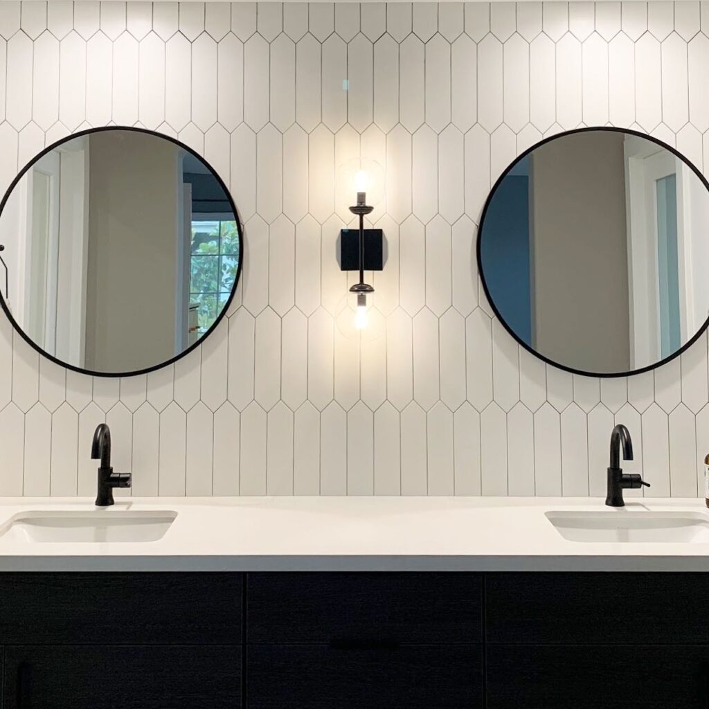 Orange County bathroom designers use white picket tile and round, black mirrors in bathroom
