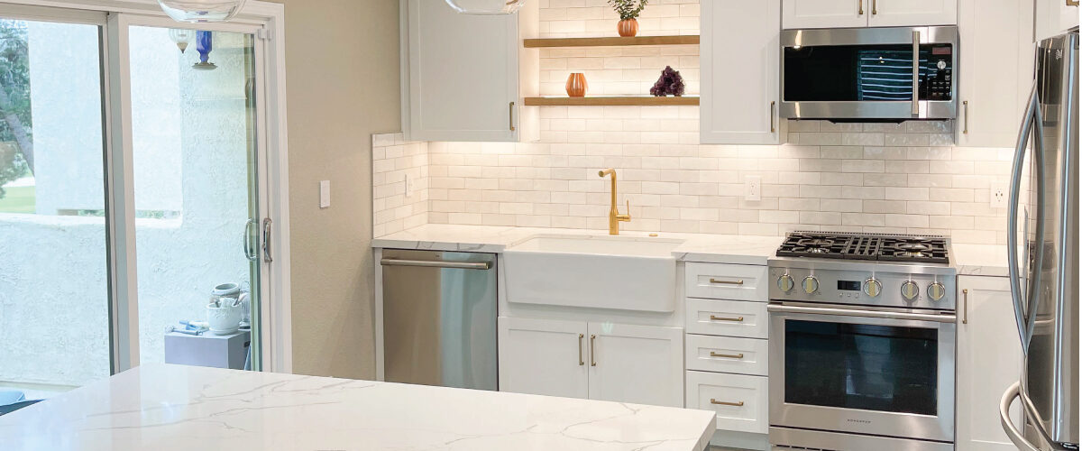 Teal and white custom cabinets in kitchen with white countertops and backsplash
