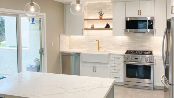 Teal and white custom cabinets in kitchen with white countertops and backsplash