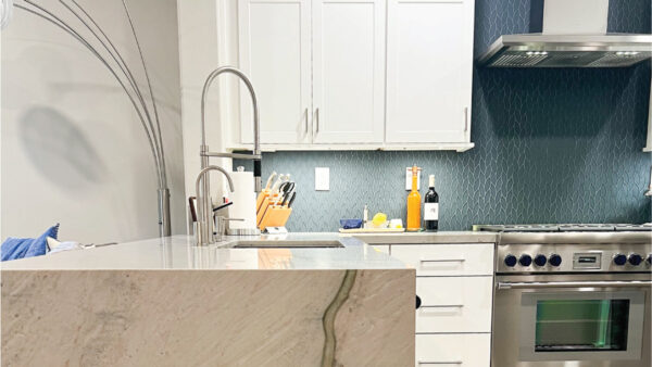 White shaker style kitchen cabinets with blue backsplash and quartzite countertops