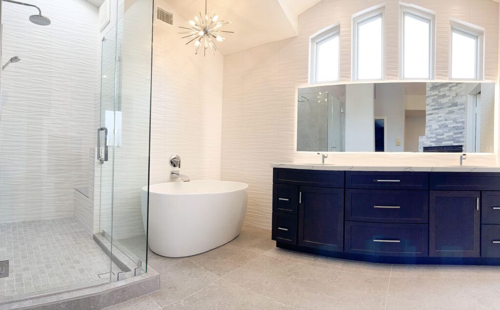 frameless shower, white soaking tub, and blue custom cabinets create a space like bathroom