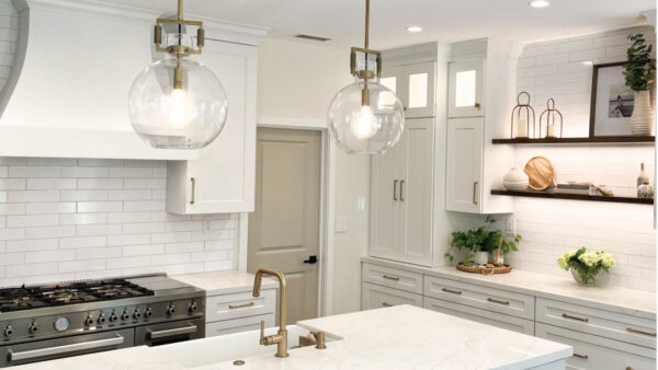 Traditional white kitchen countertops and cabinetry with gold accessories and wood shelving