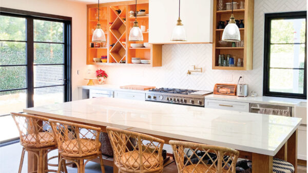 Wood-toned cabinets with custom white hood and seating at island with Boho feel