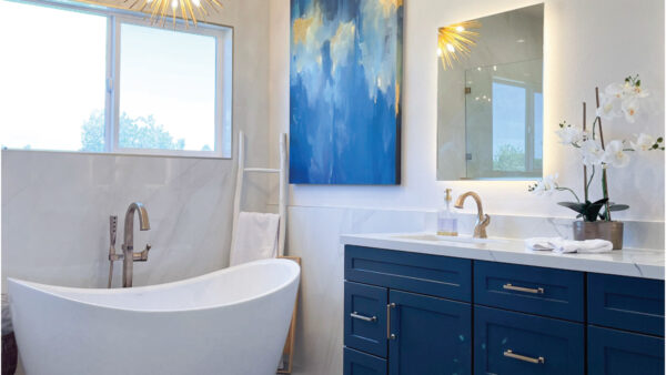 Coastal transitional master ensuite with navy cabinets and white stand alone tub