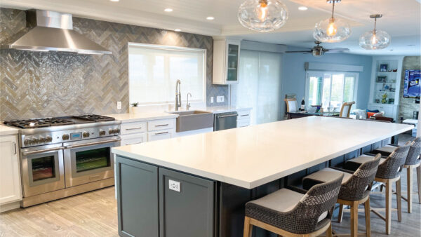 Grey and white kitchen cabinetry with large island and stainless appliances in open concept custom kitchen remodeling