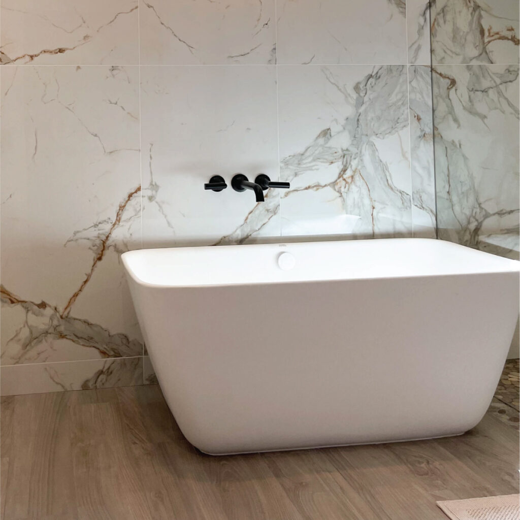 Orange County flooring contractor uses wood-look tile to create spa feeling with white marble walls and white soaking tub