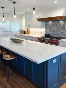 Spanish inspired kitchen renovation with white and blue cabinetry, wood accents, and Spanish style backsplash