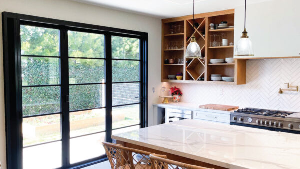 After kitchen remodeler adds open shelves storing white cups and plates