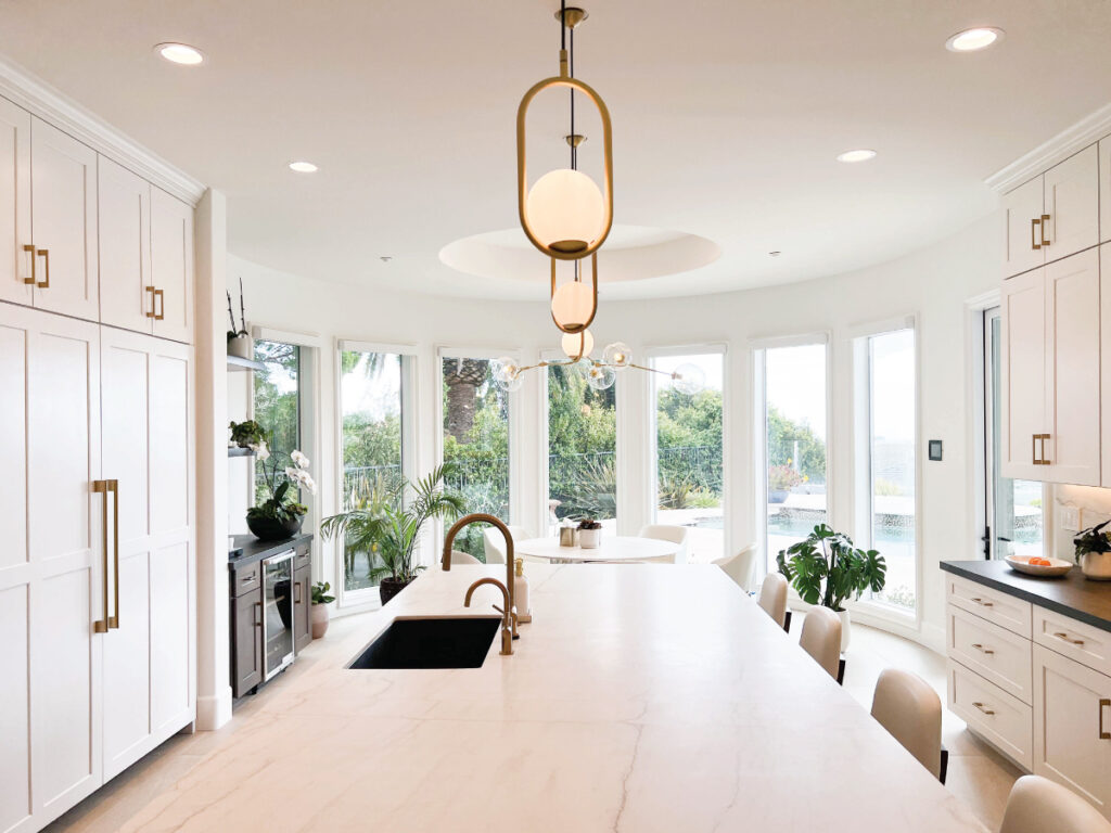 White kitchen cabinetry with gold accessories and light countertops