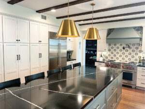 kitchen and bath contractors after picture with gold lamps, white cabinets, and black counters