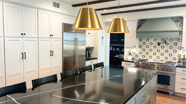 kitchen and bath contractors after picture with gold lamps, white cabinets, and black counters