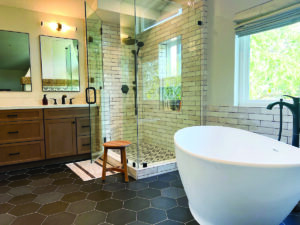 Wood toned master bath vanity with black hexagon tile