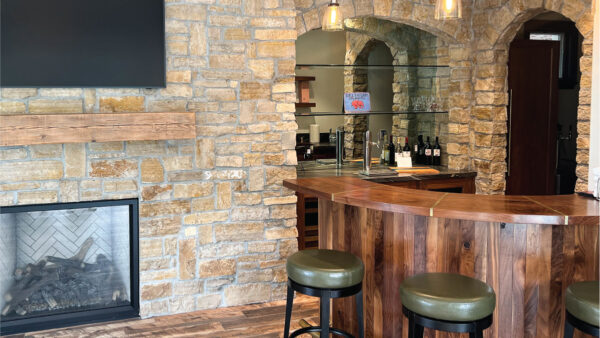 Orange County general contractor creates the feel of a European pub in a modern house with stone fireplace and wood bar