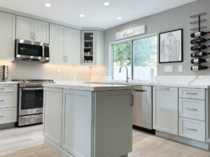 Kitchen remodeling after: light grey cabinets, white quartz countertops, and light grey tile floors