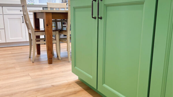 Orange County flooring contractor photo after installing wood LVP in kitchen with green cabinets and white countertop