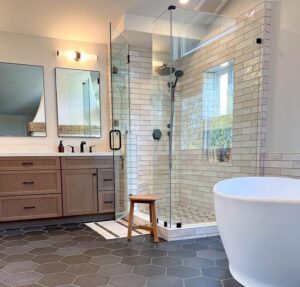 local bathroom remodeling contractors (Orange County) after photo with seamless glass shower, white soaking tub, dual mirrors, and 3 contrasting tile patterns