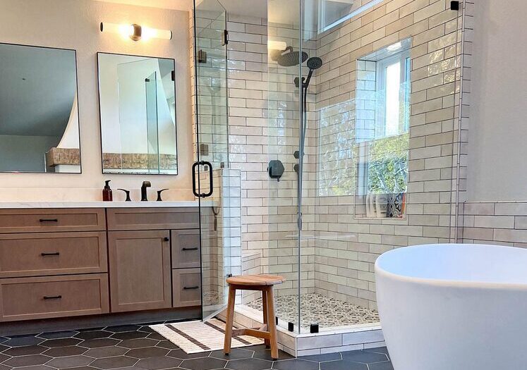 local bathroom remodeling contractors (Orange County) after photo with seamless glass shower, white soaking tub, dual mirrors, and 3 contrasting tile patterns