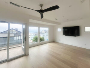 Living room on the coast with views of the ocean through large window and folding door system with wood flooring