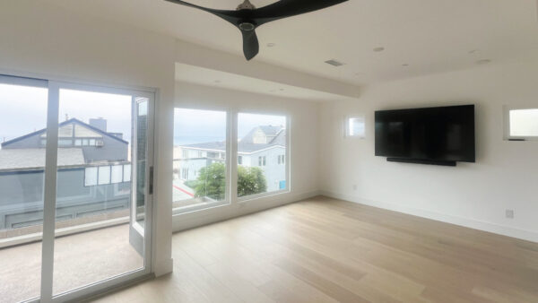 Living room on the coast with views of the ocean through large window and folding door system with wood flooring