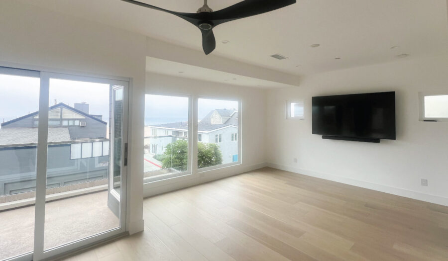 Living room on the coast with views of the ocean through large window and folding door system with wood flooring