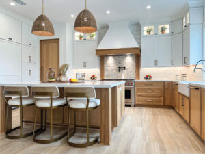White and white oak kitchen cabinetry with pendant lighting and light wood-tone porcelain floors