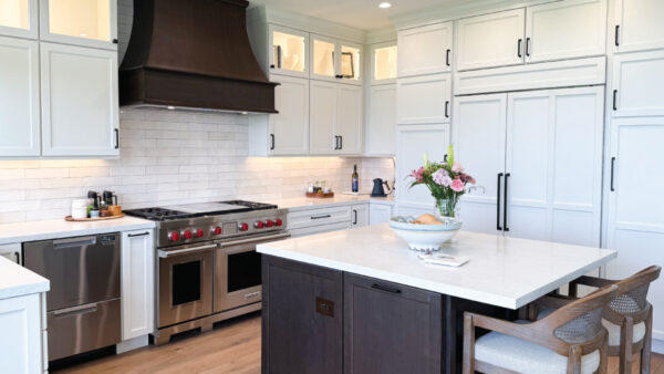 Two tone kitchen with white and dark wood tone cabinetry with medium wood tone vinyl flooring and stainless steel appliances