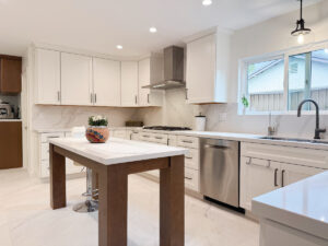 Kitchen remodeling after: Bright white cabinets with warm wood tone accents and freestanding marble island