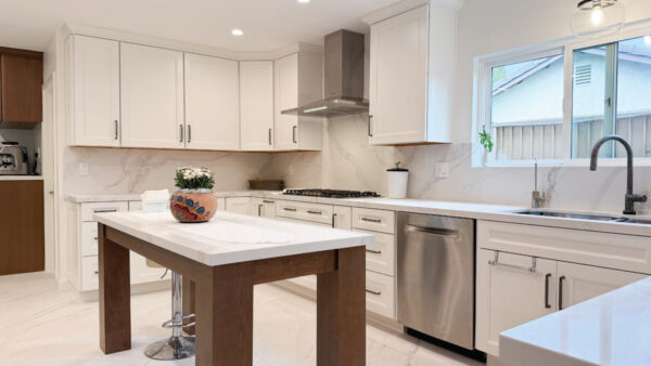 Bright white kitchen with warm wood tone accents including freestanding island with white marble-look quartz countertops and porcelain tile floor