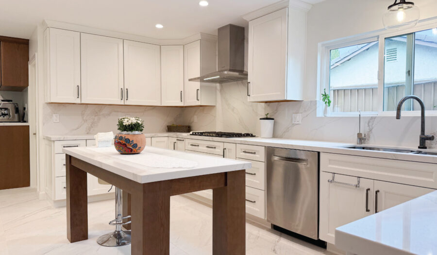 Kitchen remodeling after: Bright white cabinets with warm wood tone accents and freestanding marble island
