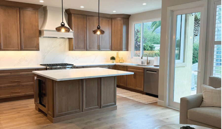 Wood tone kitchen cabinets with statement white hood and quartz countertops, with a lighter tone engineered hardwood floor.