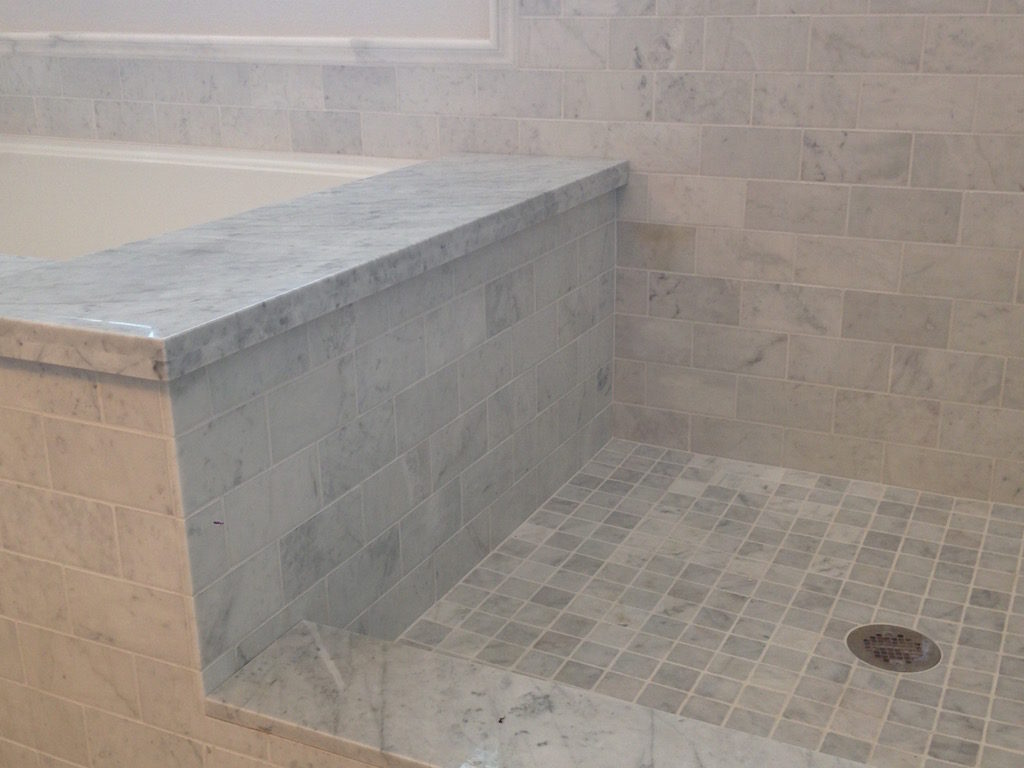 bathroom contractor shows how he mixed carrara and calacatta tle in the shower